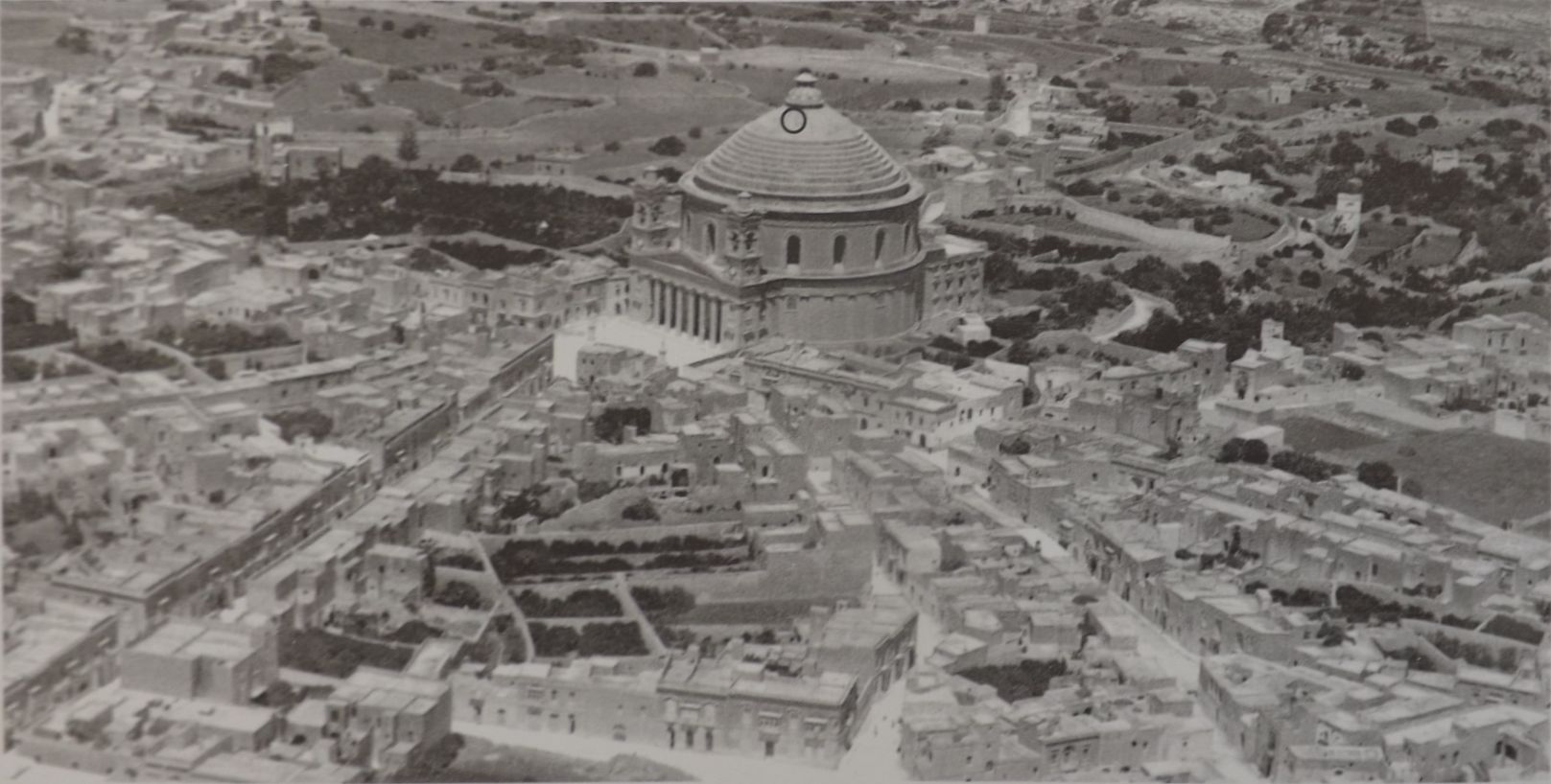 Aerial photo of the Mosta Rotunda in a pre-war photograph with circle marking where the bomb pierced the dome